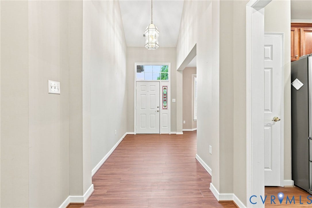 Foyer featuring high ceilings, wood-finish flooring, a decorative pendant light, and a paneled entry door with sidelights