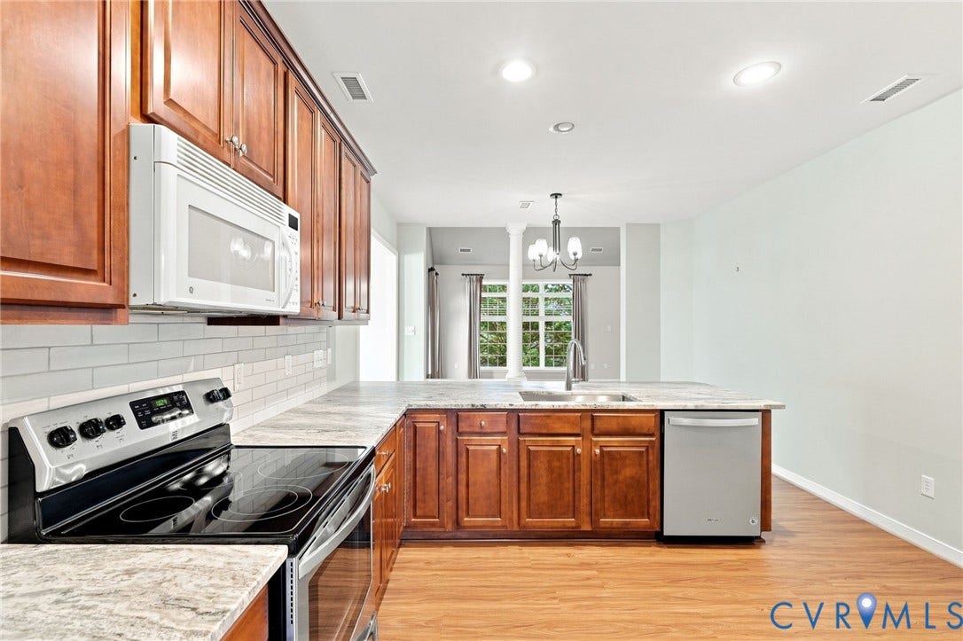 Kitchen featuring wood-finish cabinetry, light-toned countertops, and a white subway tile backsplash