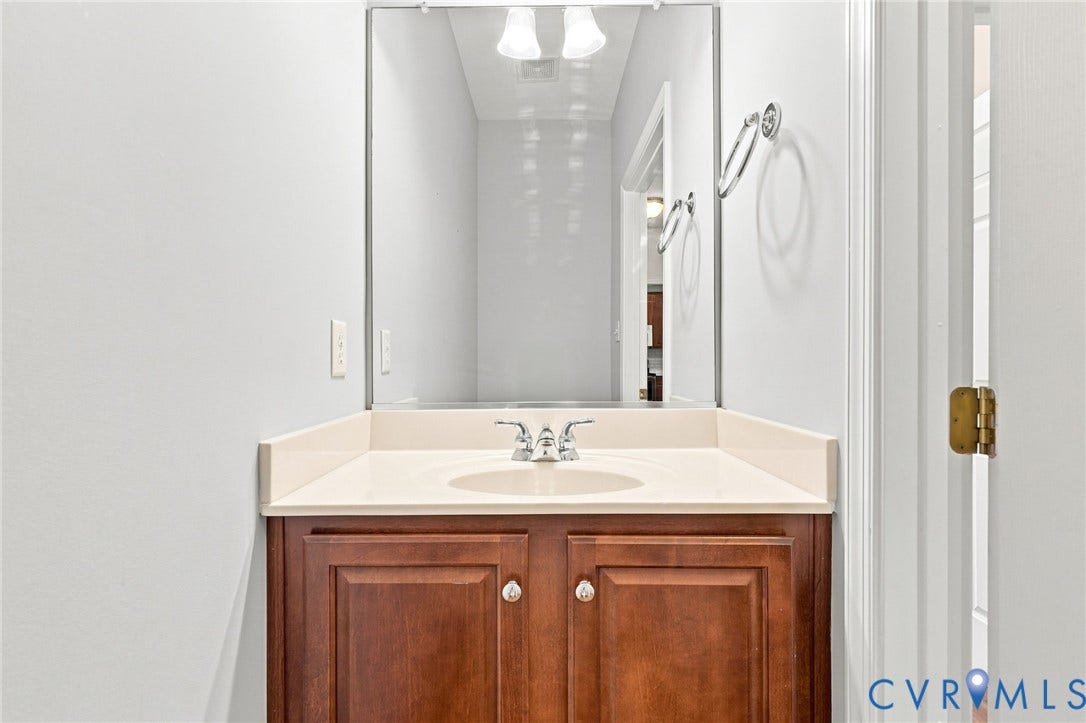Vanity featuring a light-colored countertop with an integrated sink, chrome-finish faucet, and warm wood-finish cabinetry