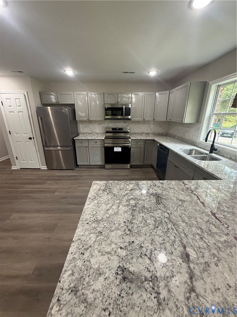 3430 The Loop Rd, Glendale, Montross, VA 23231 Kitchen featuring ample cabinetry, stainless steel appliances, dual basin sink, wood-finish flooring, and speckled countertops