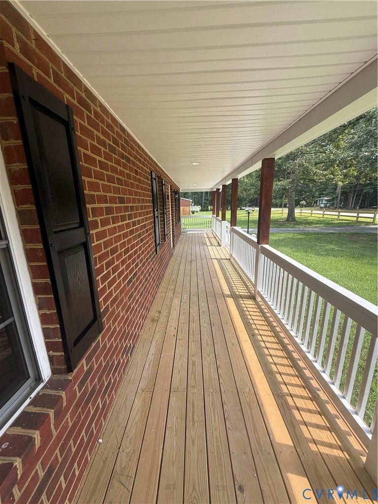3430 The Loop Rd, Glendale, Montross, VA 23231 Expansive covered porch featuring a wooden deck, red brick exterior, white railing, and dark shutters