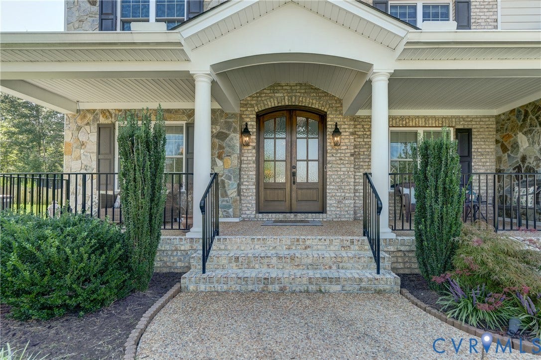 11515 Grey Oaks Estates Run, Grey Oaks Estates, Glen Allen, VA 23059 Covered porch with white columns, brick and stone facade, arched wooden entry doors, and black metal railings