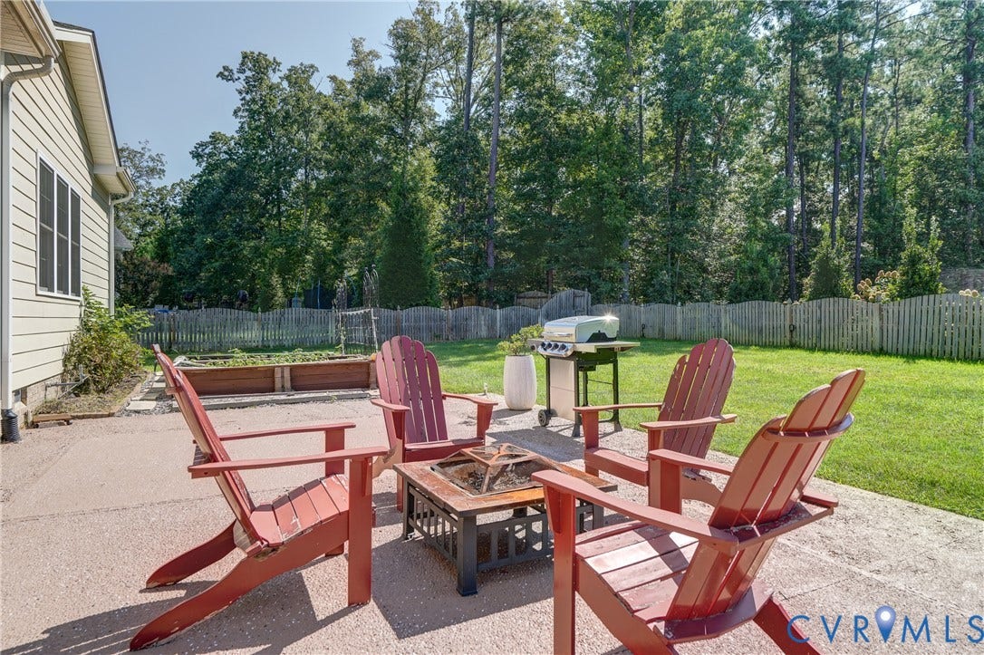 11515 Grey Oaks Estates Run, Grey Oaks Estates, Glen Allen, VA 23059 Expansive backyard featuring a concrete patio, a manicured lawn, raised garden beds, and a perimeter fence