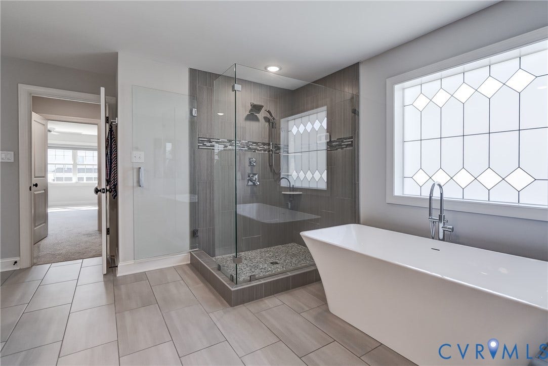 11515 Grey Oaks Estates Run, Grey Oaks Estates, Glen Allen, VA 23059 Freestanding soaking tub with chrome faucet, tiled walk-in shower with glass enclosure, decorative frosted window, and large format tile flooring