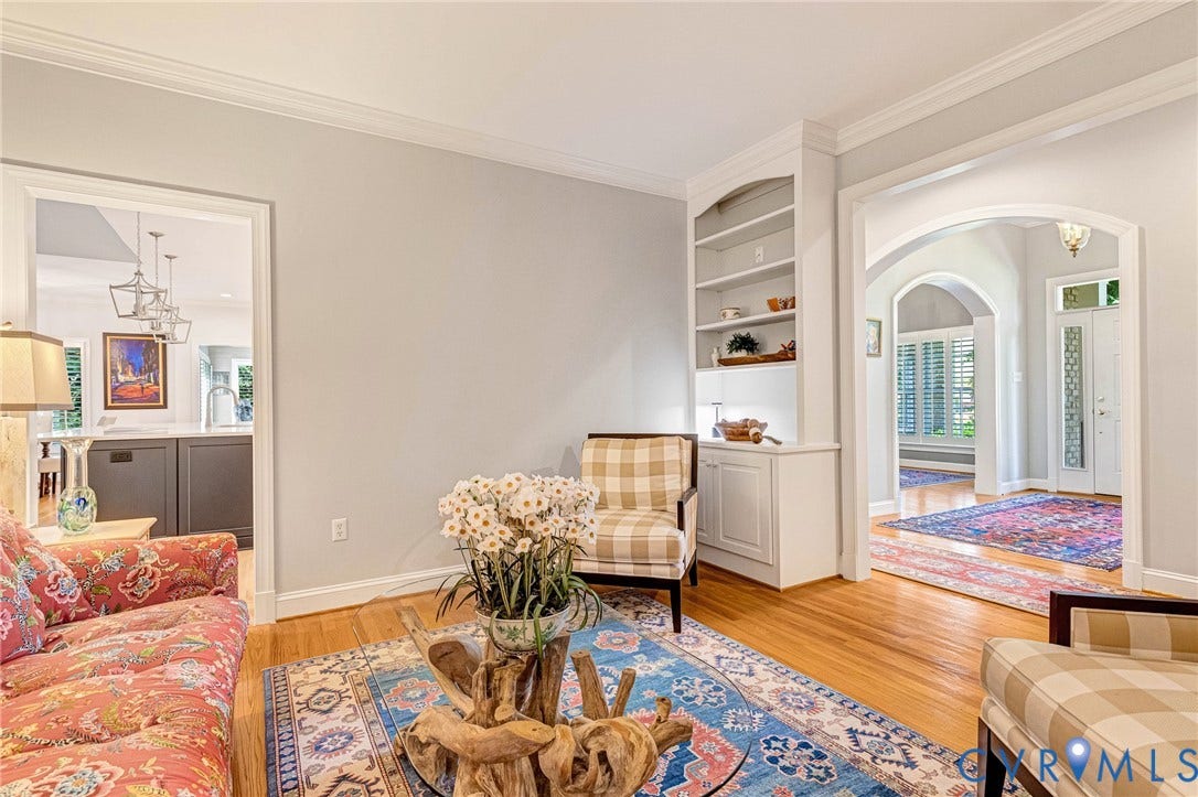 Hardwood flooring throughout, built-in shelving, crown molding, and an arched doorway
