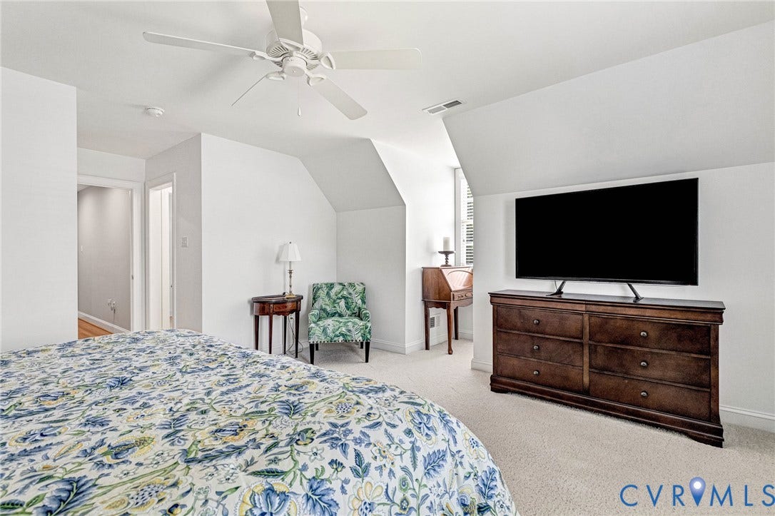 Pitched ceiling design, white painted walls, and light-toned carpeting