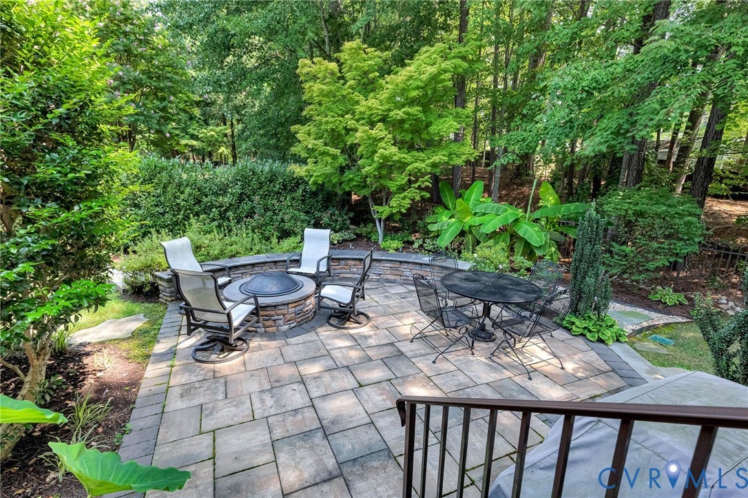 Paver patio featuring a built-in fire pit with stone surround and a stone retaining wall