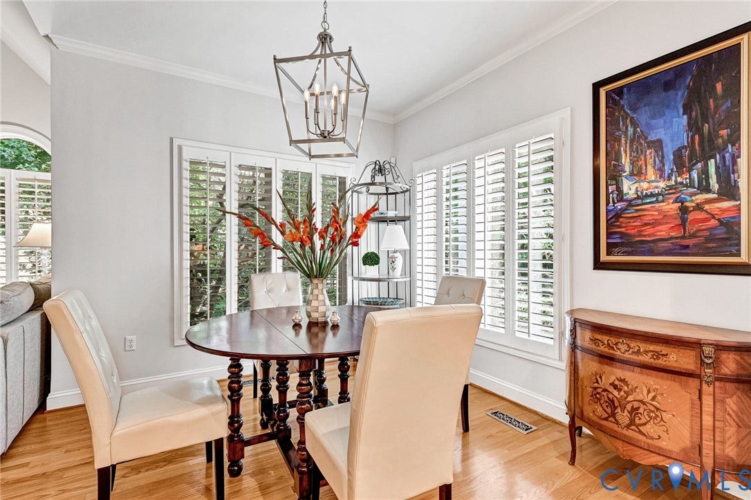 Wood-finish flooring, white plantation shutters, built-in wall niche, and crown molding