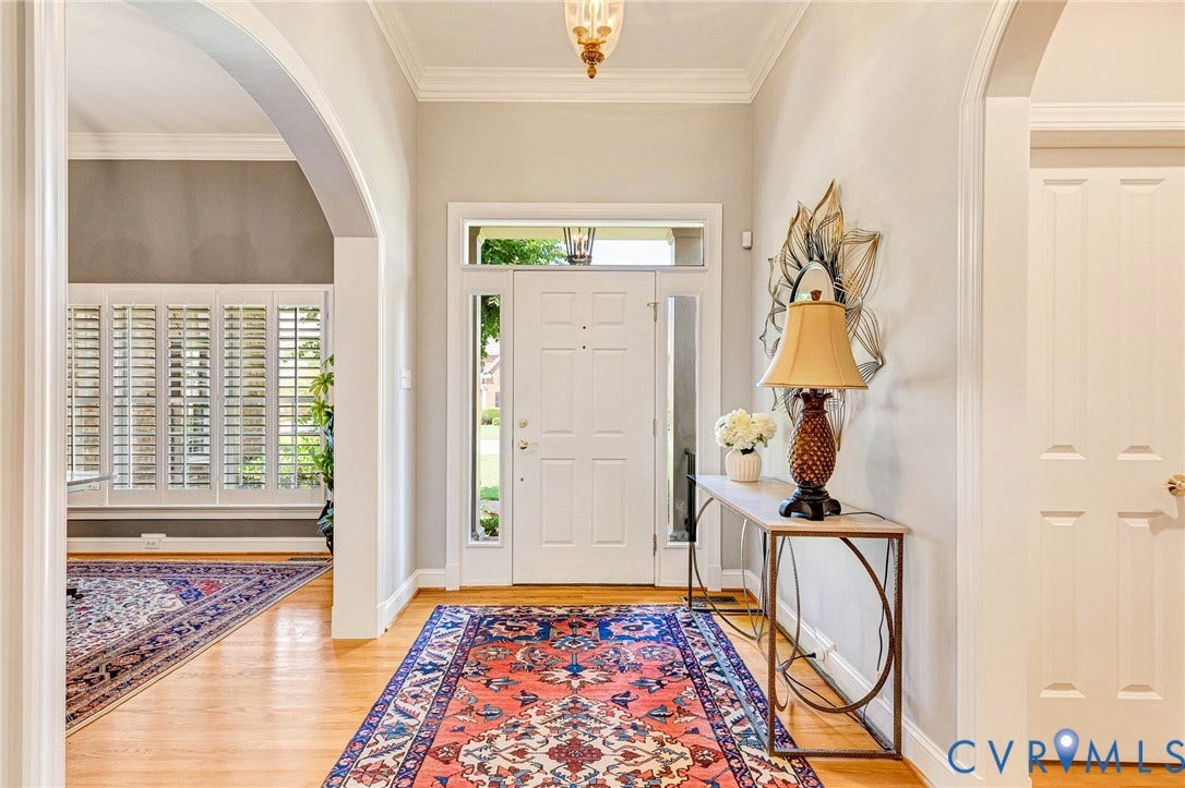 Hardwood flooring throughout entry, arched doorway, paneled interior door, transom window, and sidelight windows