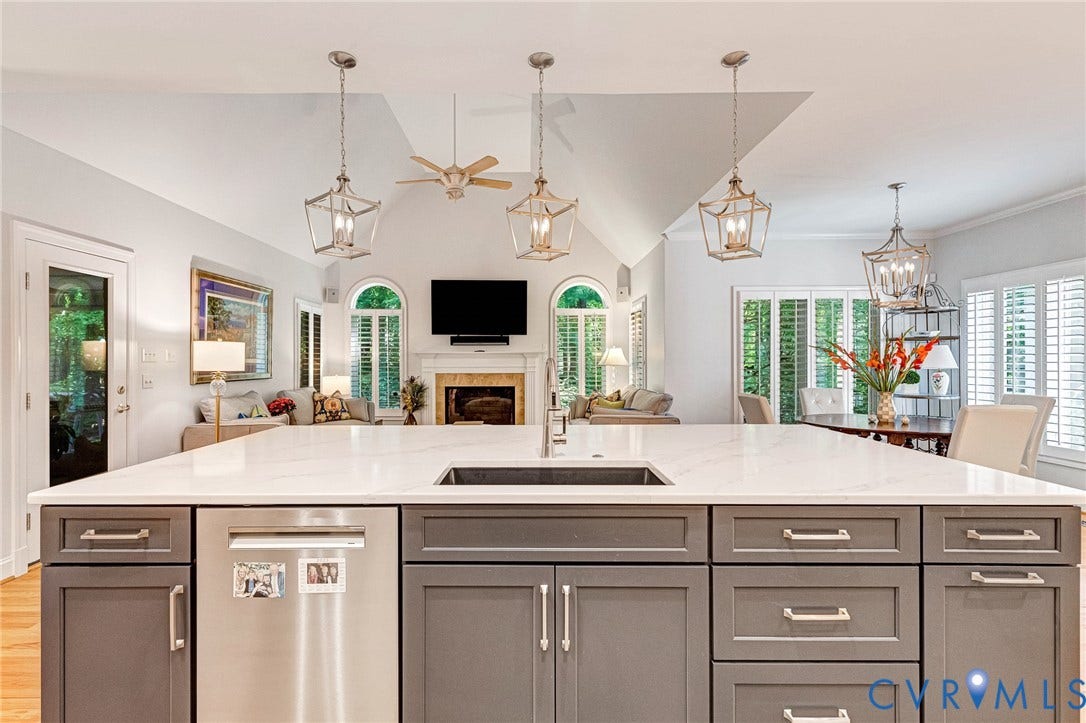 Kitchen island with integrated sink and dishwasher, featuring a light-toned countertop and gray cabinetry