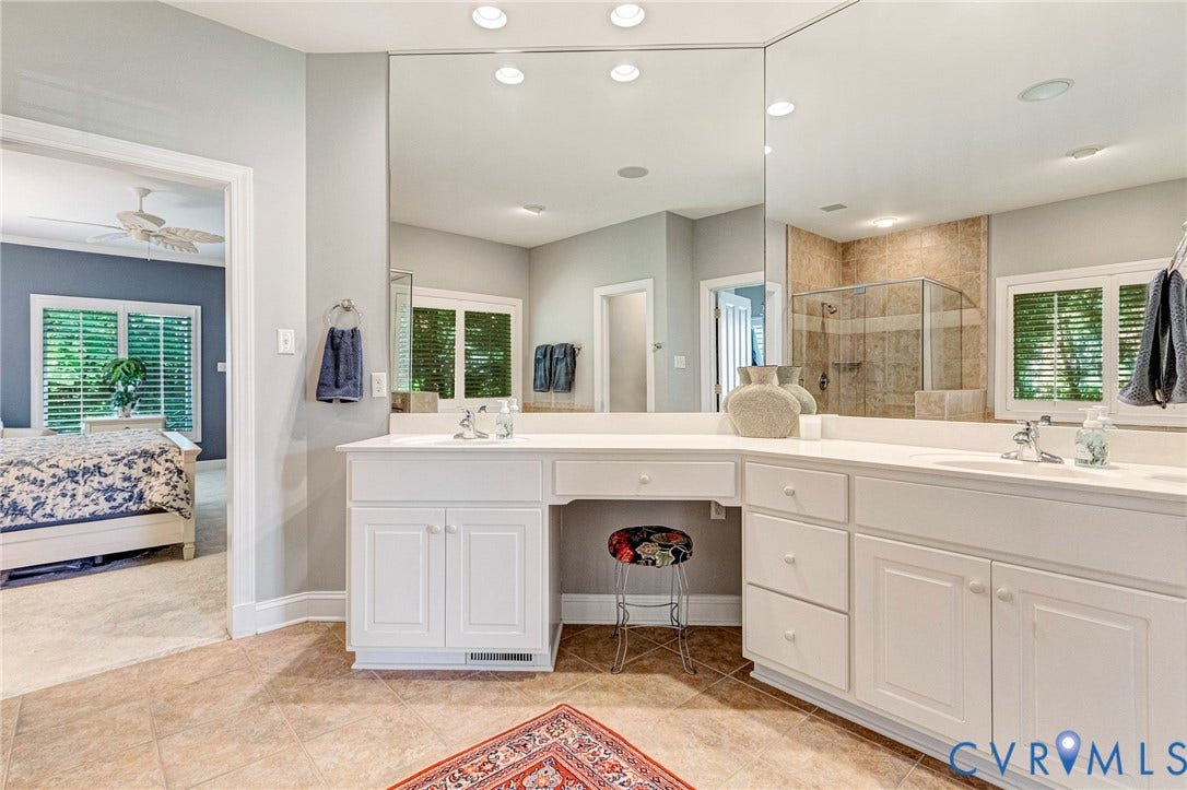 Dual vanity with integrated sinks, expansive mirror, white cabinetry, and tile flooring