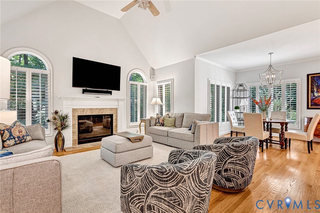 Vaulted ceiling, hardwood flooring, fireplace with stone surround, plantation shutters, and ceiling fan