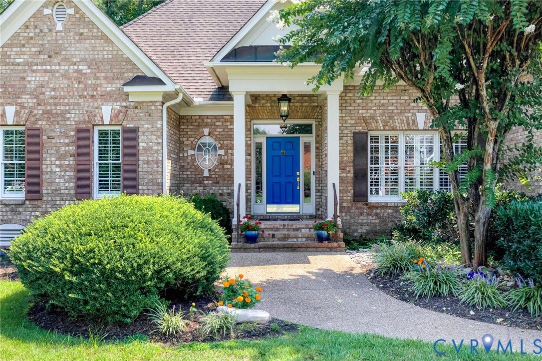 Brick exterior with white window shutters and a vibrant blue entry door