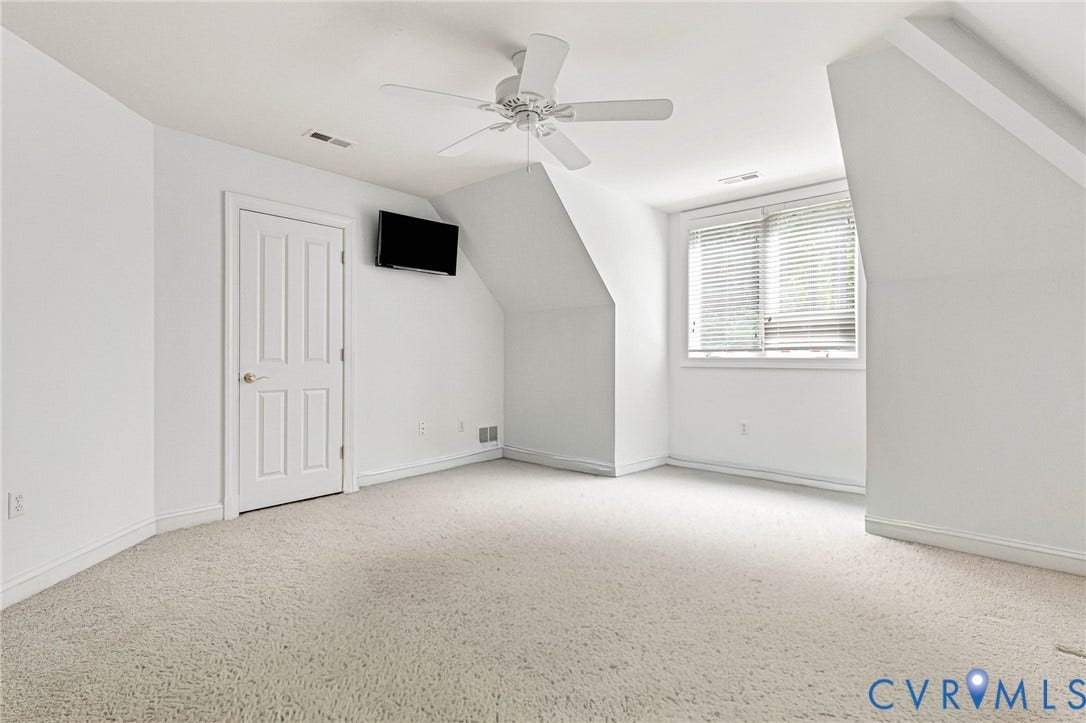 Carpeted room featuring a ceiling fan, a window with horizontal blinds, and a paneled door