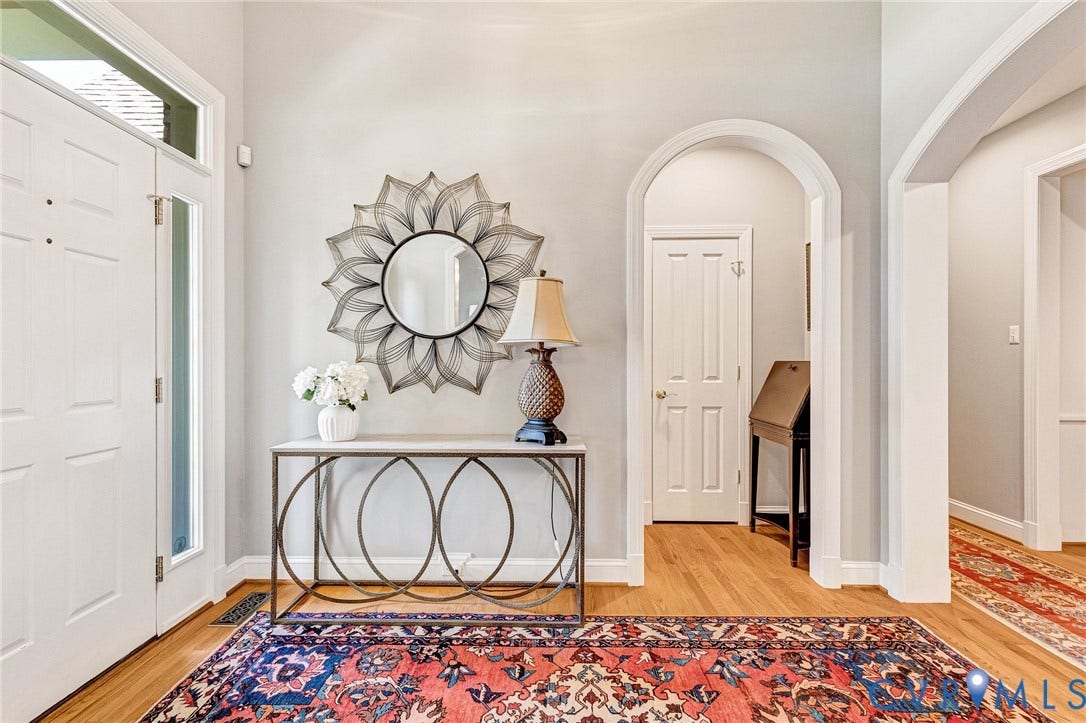 Hardwood flooring throughout, arched doorways, white paneled doors, and a decorative console table with a stone surface