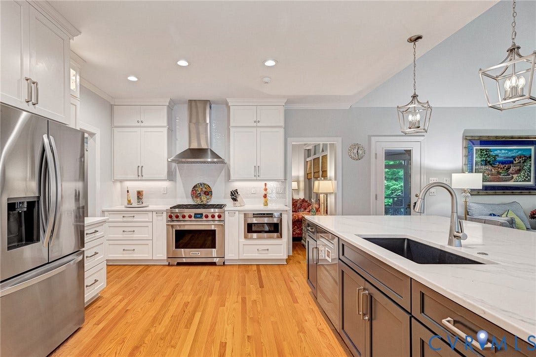 Kitchen featuring stainless steel appliances, white cabinetry, wood-finish flooring, a kitchen island with an undermount sink, and recessed lighting