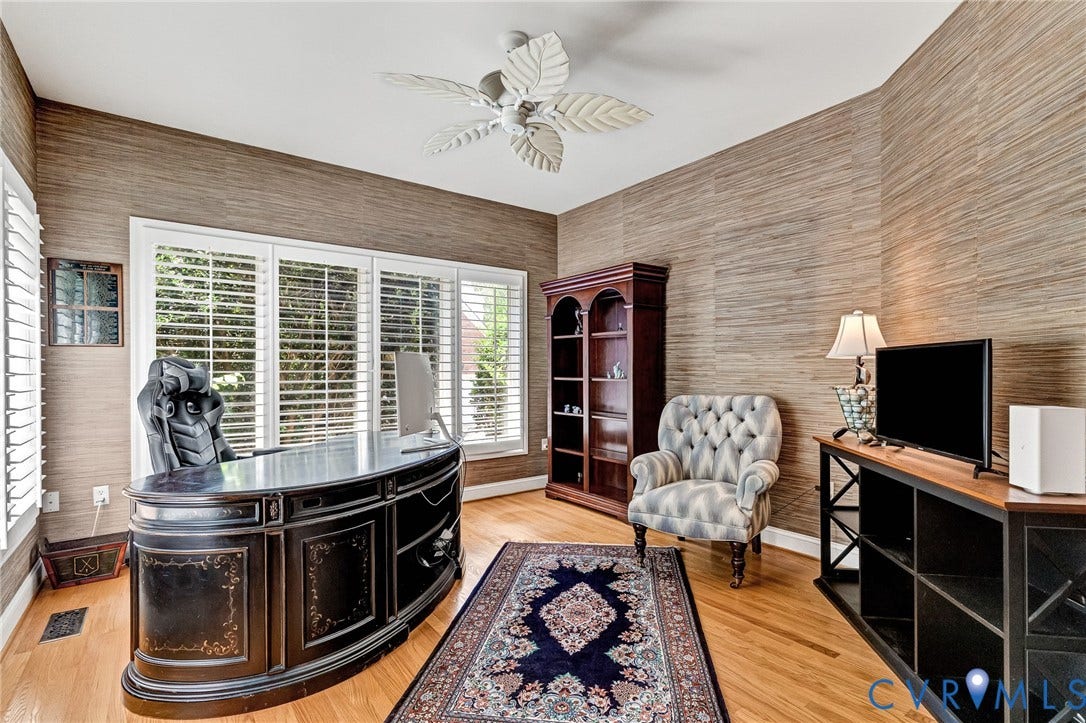 Hardwood flooring, grasscloth wallcovering, plantation shutters, multi-pane windows, and a ceiling fan with leaf-shaped blades