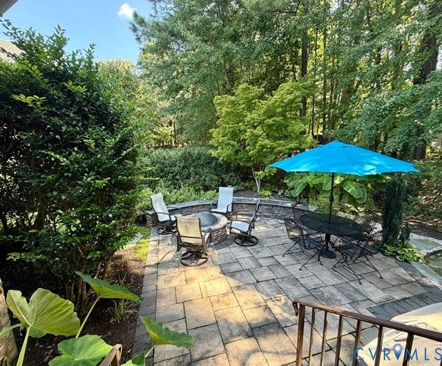 Expansive paver patio featuring a built-in stone fire pit and a tiered stone retaining wall