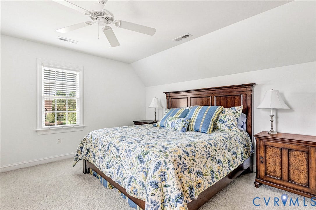 White walls with sloped ceiling, window with white blinds, ceiling fan, and carpeted flooring