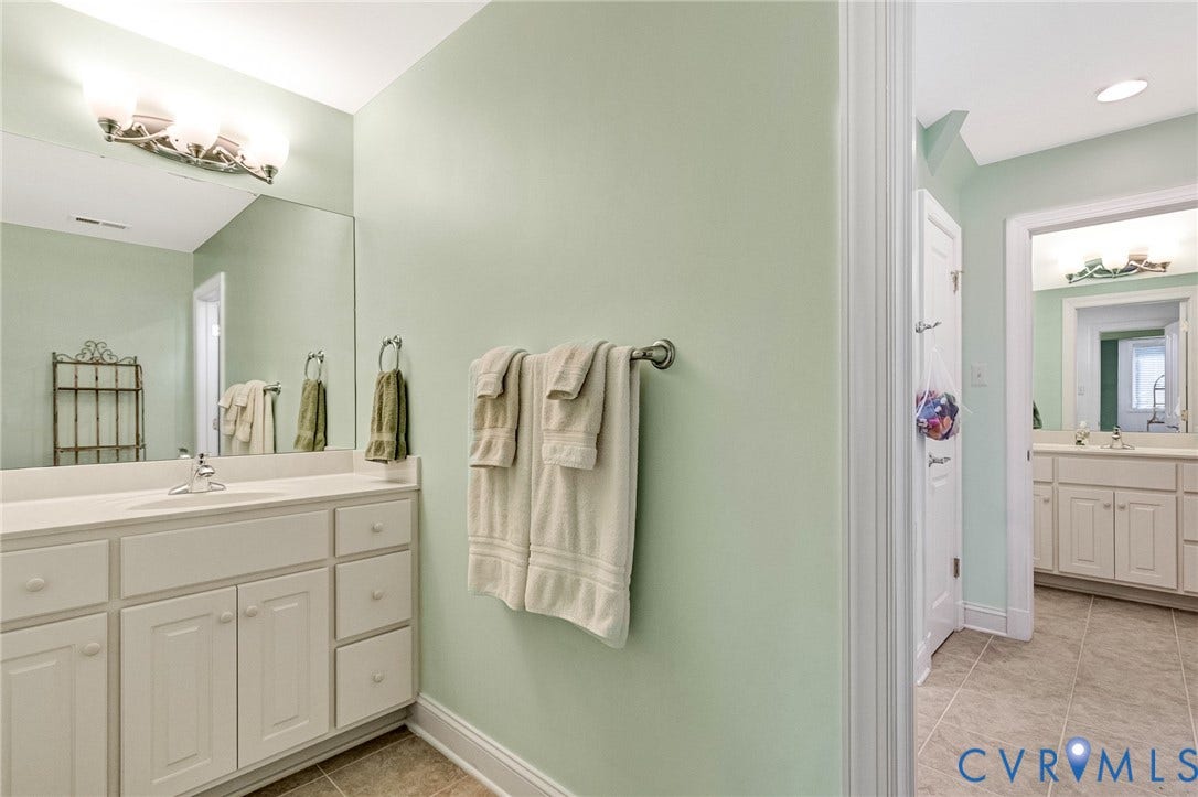 Dual vanity with white cabinetry and integrated sinks, oversized mirrors, and tile flooring