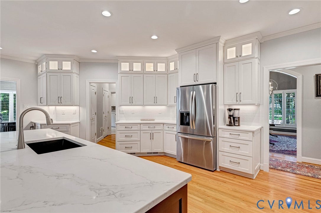 Kitchen featuring white cabinetry with upper glass-front display cabinets, stainless steel refrigerator, white subway tile backsplash, recessed lighting, and wood-finish flooring