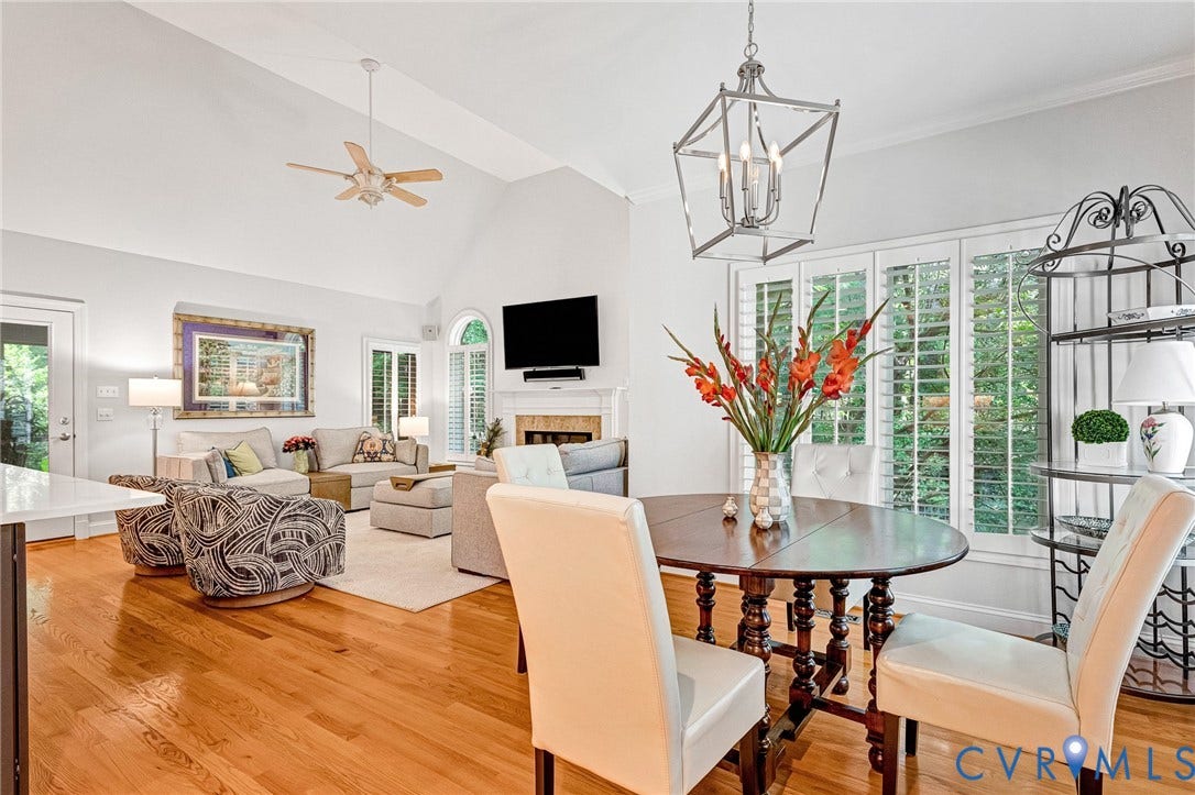 Hardwood flooring, vaulted ceiling, white interior shutters, built-in fireplace, and a contemporary chandelier