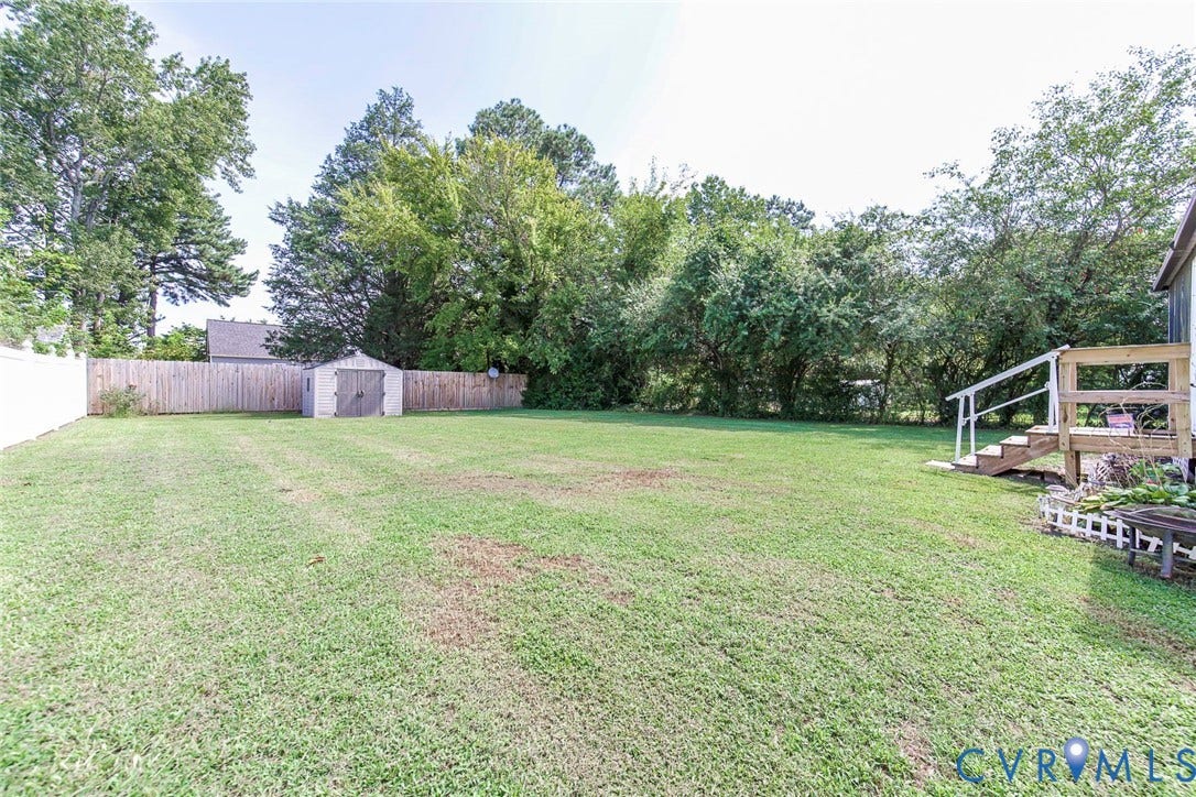 2765 Meadowbrook Street, Petersburg, VA 23803 Expansive grassy yard with a privacy fence, wood-finished deck, and a storage shed