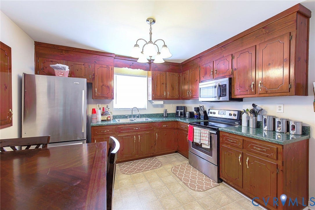 2765 Meadowbrook Street, Petersburg, VA 23803 Kitchen featuring wood cabinetry, stainless steel appliances, a double basin sink, and a multi-light chandelier