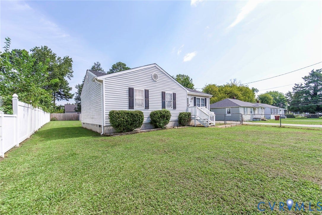 2765 Meadowbrook Street, Petersburg, VA 23803 Single-story residence featuring light-colored siding, dark shutters, and a white fence