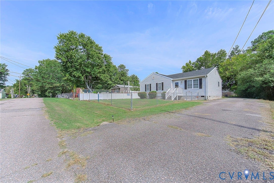 2765 Meadowbrook Street, Petersburg, VA 23803 Ranch-style exterior with light-toned siding and dark shutters, featuring a front porch with white railings, a fenced yard, and an asphalt driveway