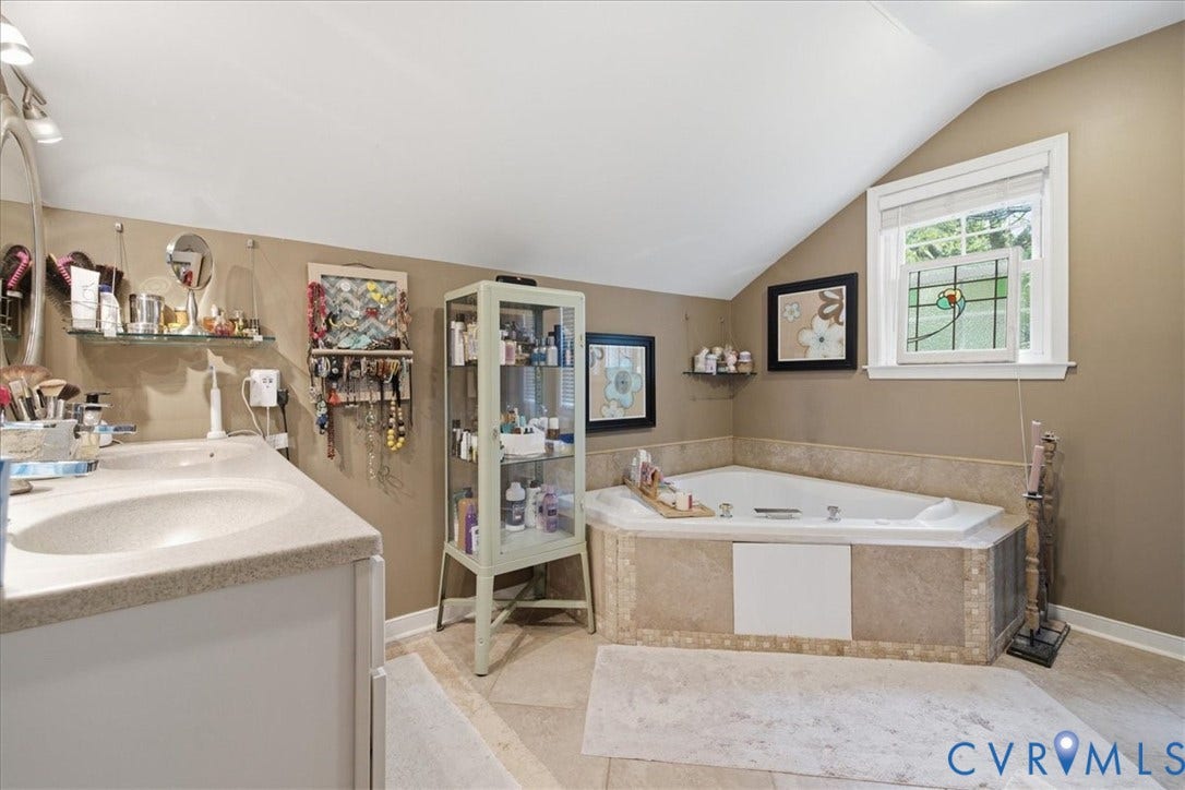 4702 New Kent Avenue, Westover Hills, Richmond, VA 23225 Angled soaking tub with tile surround, a built-in vanity with single basin, and a window with stained glass detail