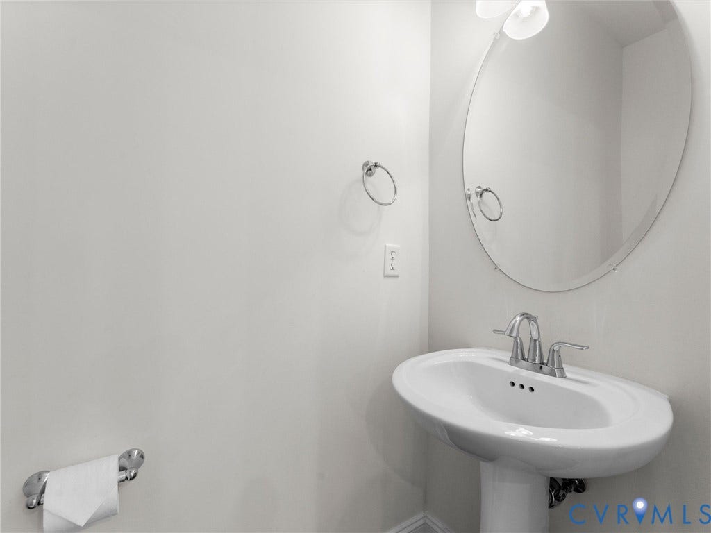 14227 Michaux Village Drive, Winterfield Park, Midlothian, VA 23113 Pedestal sink with chrome faucet, oval mirror, and wall-mounted light fixture