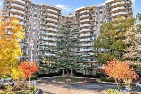 High-rise building with multiple levels of private balconies, a circular driveway, and mature landscaping