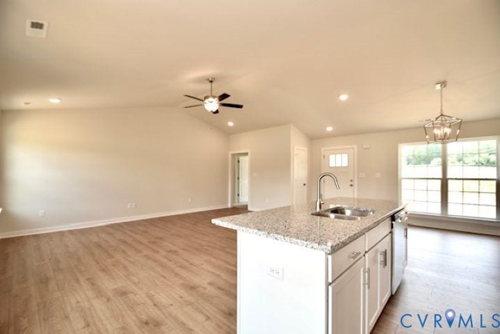 410 Kents Mill Rd, Louisa, VA 23093 Open-concept living area featuring a kitchen island with stone-finish countertops, wood-finish flooring, a vaulted ceiling, and recessed lighting