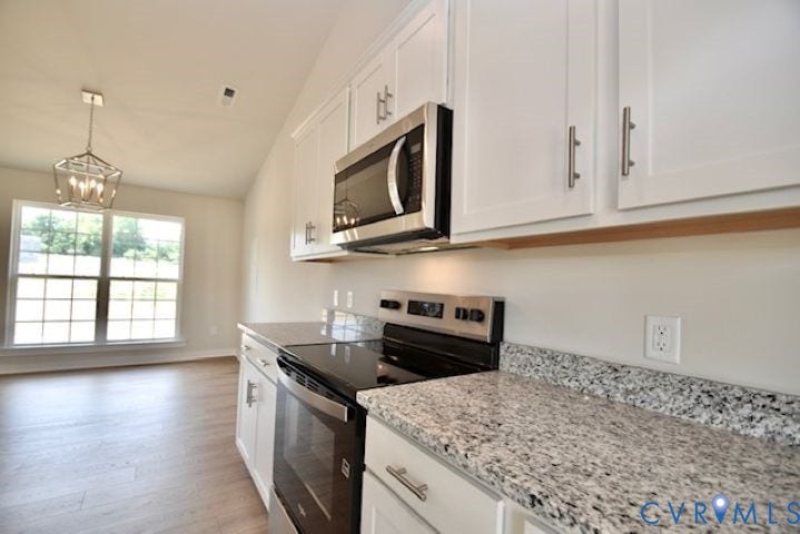 410 Kents Mill Rd, Louisa, VA 23093 Kitchen featuring white cabinetry, stainless steel appliances, granite-style countertops, wood-finish flooring, and a vaulted ceiling