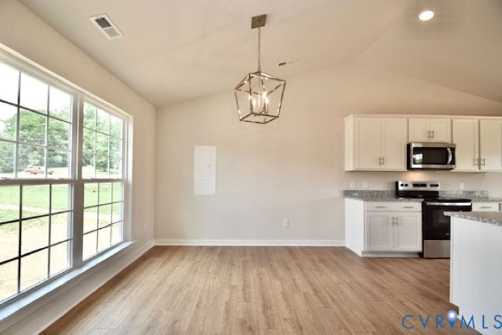410 Kents Mill Rd, Louisa, VA 23093 Vaulted ceiling with a contemporary chandelier, wood-finish flooring, white cabinetry with silver hardware, stainless steel microwave, and a black range