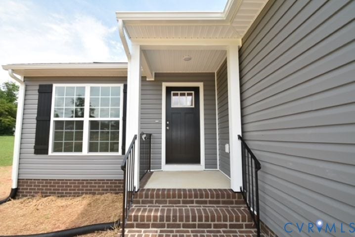 410 Kents Mill Rd, Louisa, VA 23093 Gray horizontal siding, white trim, black door with transom window, white multi-pane window with black shutters, and brick steps with black railing