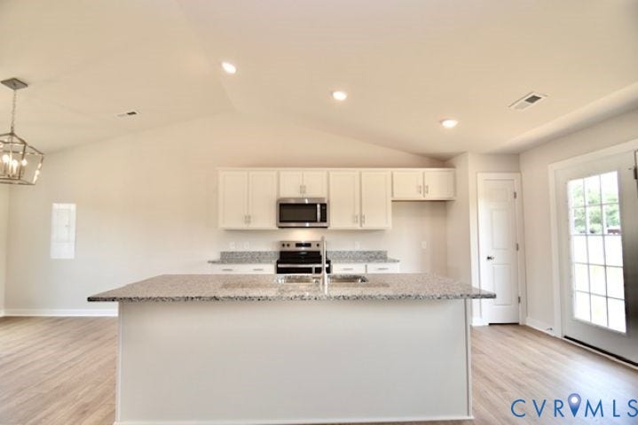 410 Kents Mill Rd, Louisa, VA 23093 Kitchen featuring an island with a built-in sink, white cabinetry, integrated stainless steel appliances, and wood-finish flooring