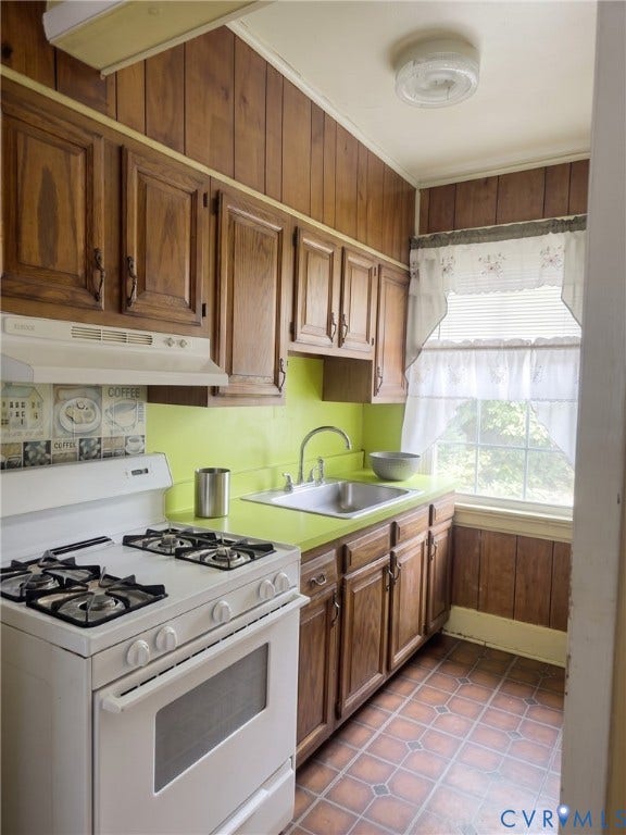 2811 Woodcliff Avenue, Richmond, VA 23222 Wood paneling accents a kitchen featuring wood cabinetry, a white gas range, and a single basin sink