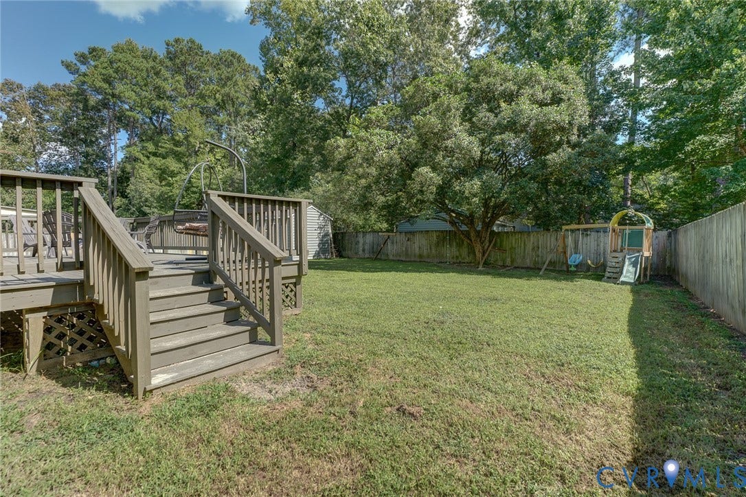4647 Brookridge Road, Chesterfield, VA 23832 Expansive backyard featuring a wood deck with stairs, a privacy fence, and mature trees