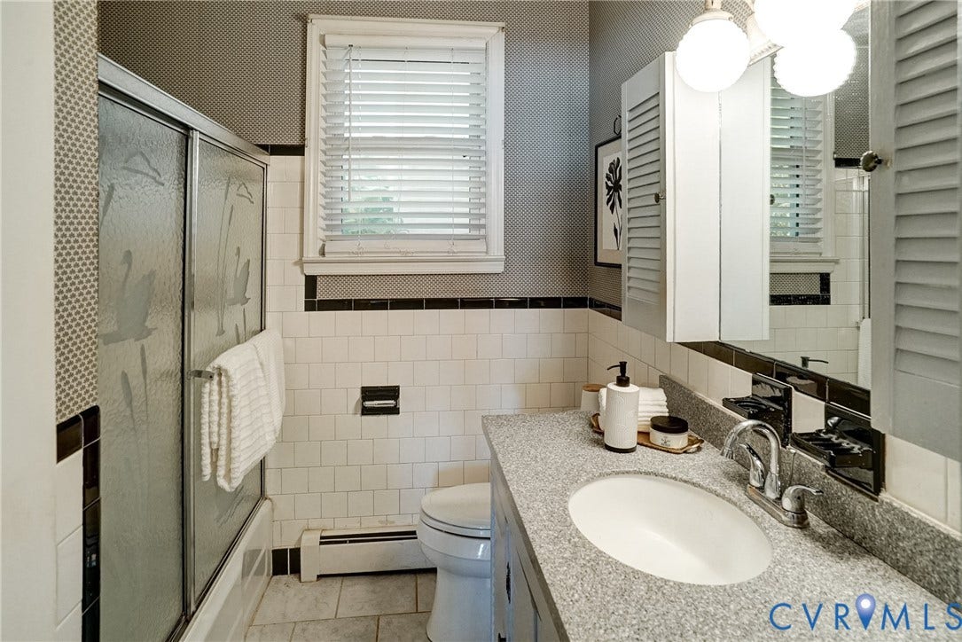 Bathroom featuring a white tub, sliding glass shower enclosure, vanity with countertop, integrated oval sink