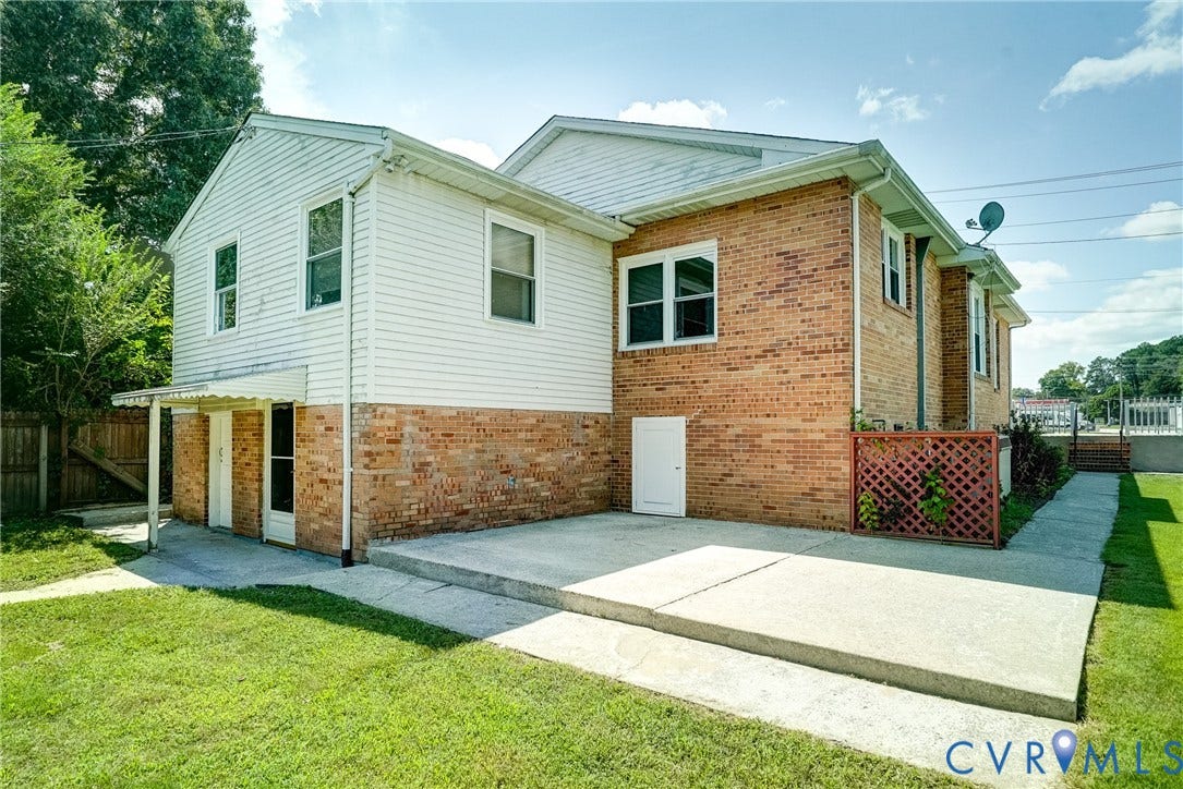 Two-story siding and brick exterior with multiple windows, concrete patio, concrete walkway