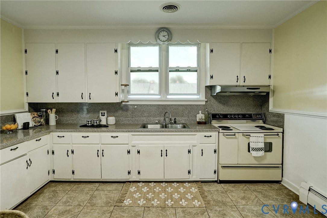 White cabinetry with black hardware, sink,  countertop, and tile flooring