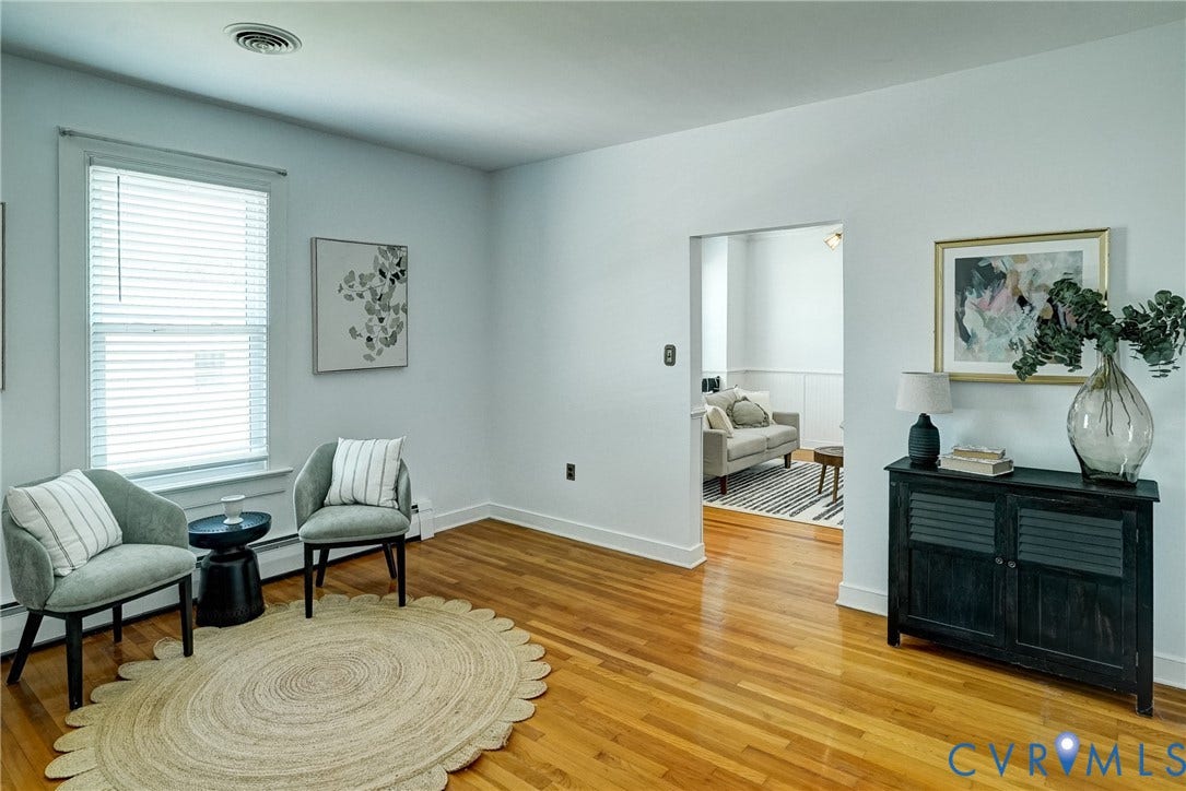 Hardwood flooring, painted white walls, white window blinds, and an open doorway to living room
