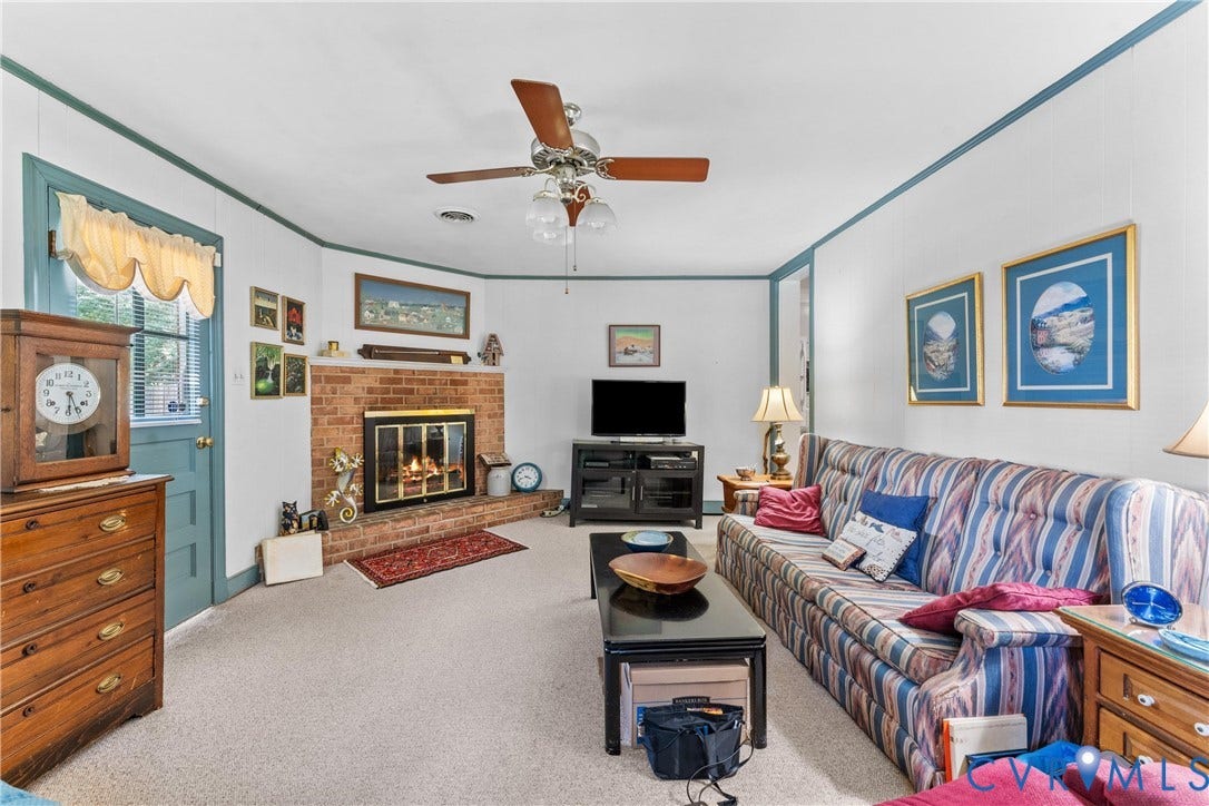 10205 Gwynnbrook Road, Richmond, VA 23235 Brick fireplace with a black metal screen, a ceiling fan with integrated lighting, and neutral carpeting