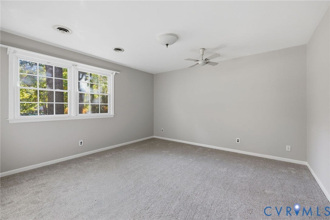 Room featuring neutral wall tones, multi-pane windows, wall-to-wall carpeting, and a ceiling fan
