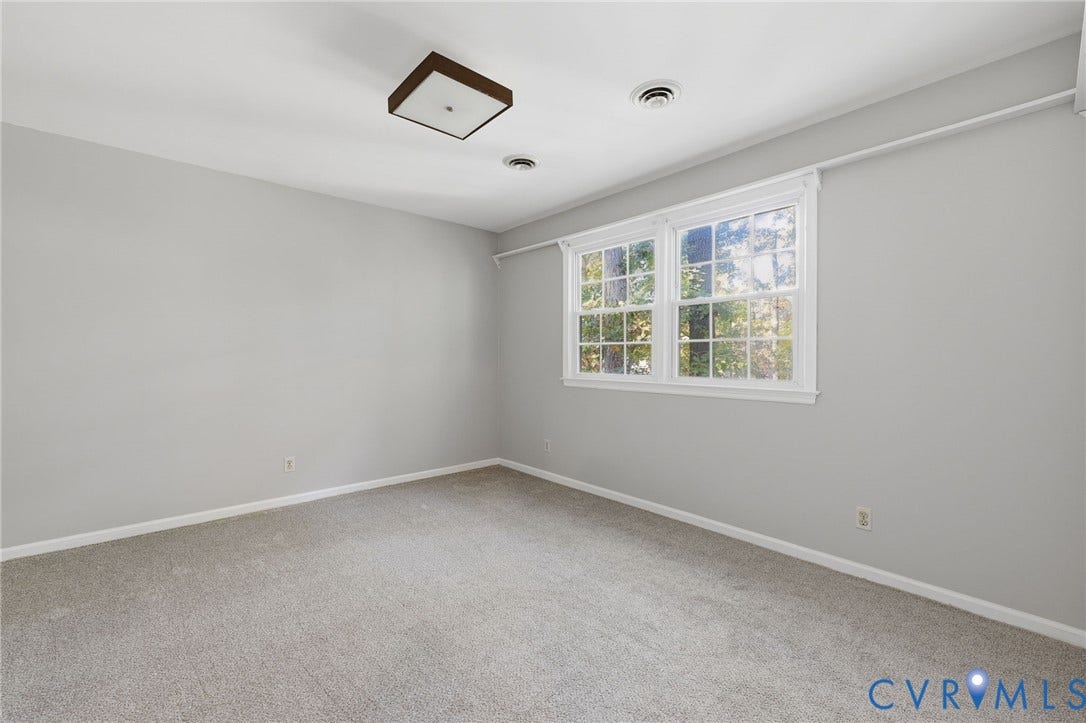 Neutral-toned walls, wall-to-wall carpeting, double-hung windows, and a flush-mount light fixture