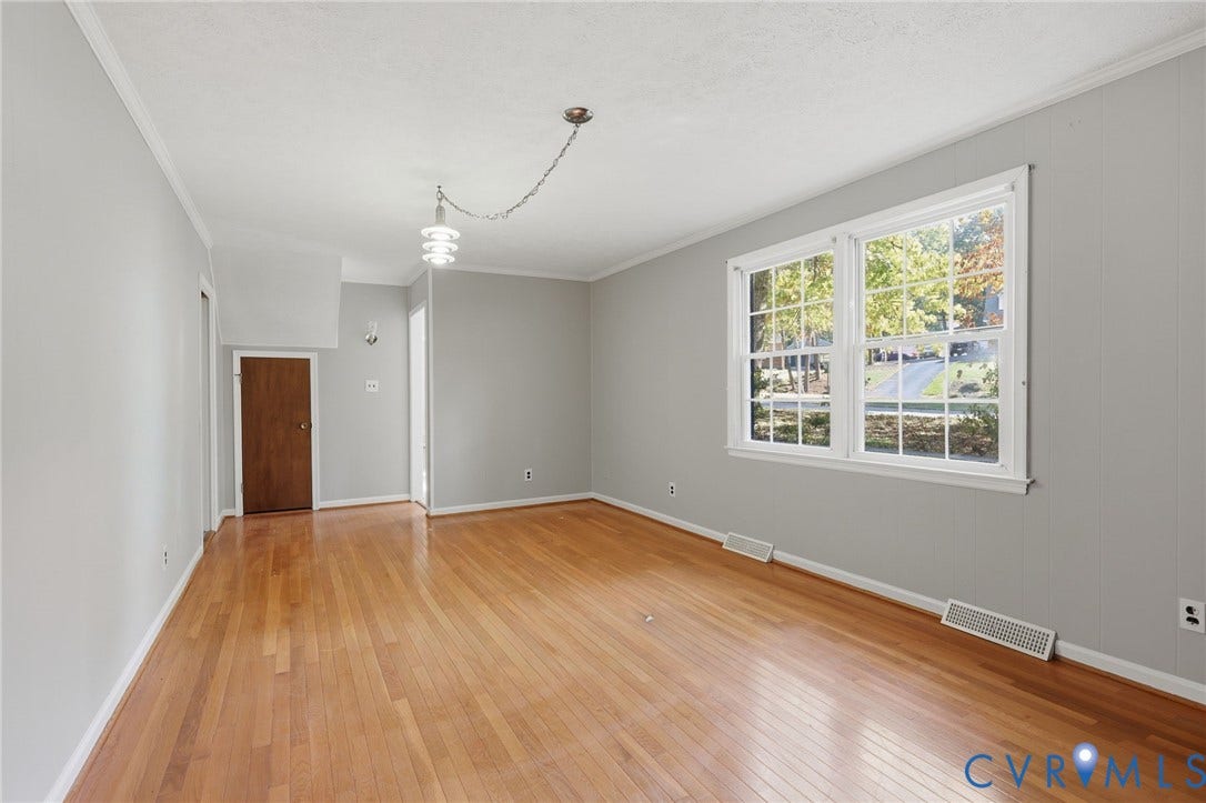 Room featuring wood-finish flooring, dual-pane windows with muntins, neutral wall color, and a multi-tiered pendant light fixture