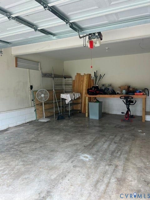 11419 Courthouse Acres Drive, Midlothian, VA 23114 Interior garage with a concrete floor, painted white walls, and an overhead garage door mechanism