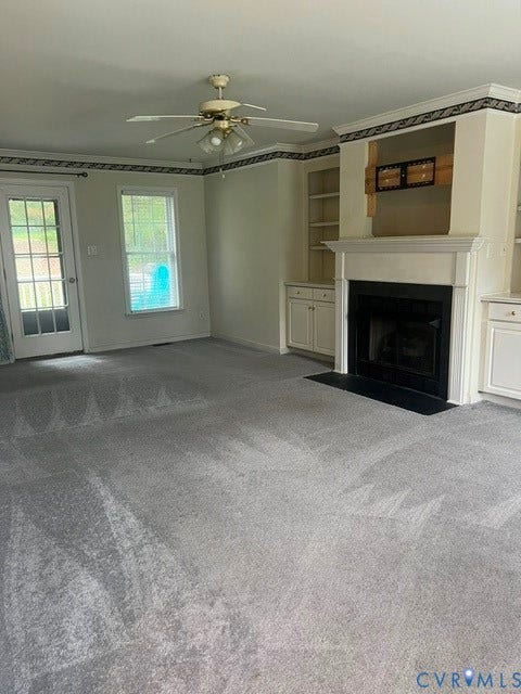 11419 Courthouse Acres Drive, Midlothian, VA 23114 Living area featuring a fireplace with a mantel, built-in shelving, glass-paned door, a window, and a ceiling fan